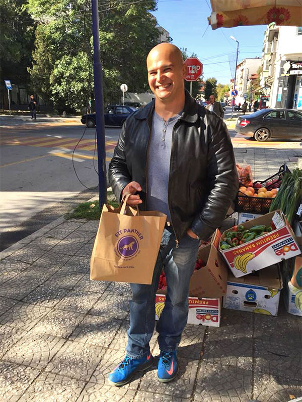 smiling customer with a package of food from Fit Panther