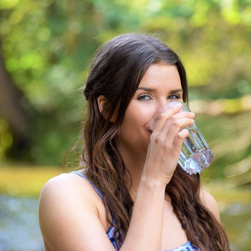 млада жена отпива вода от чаша