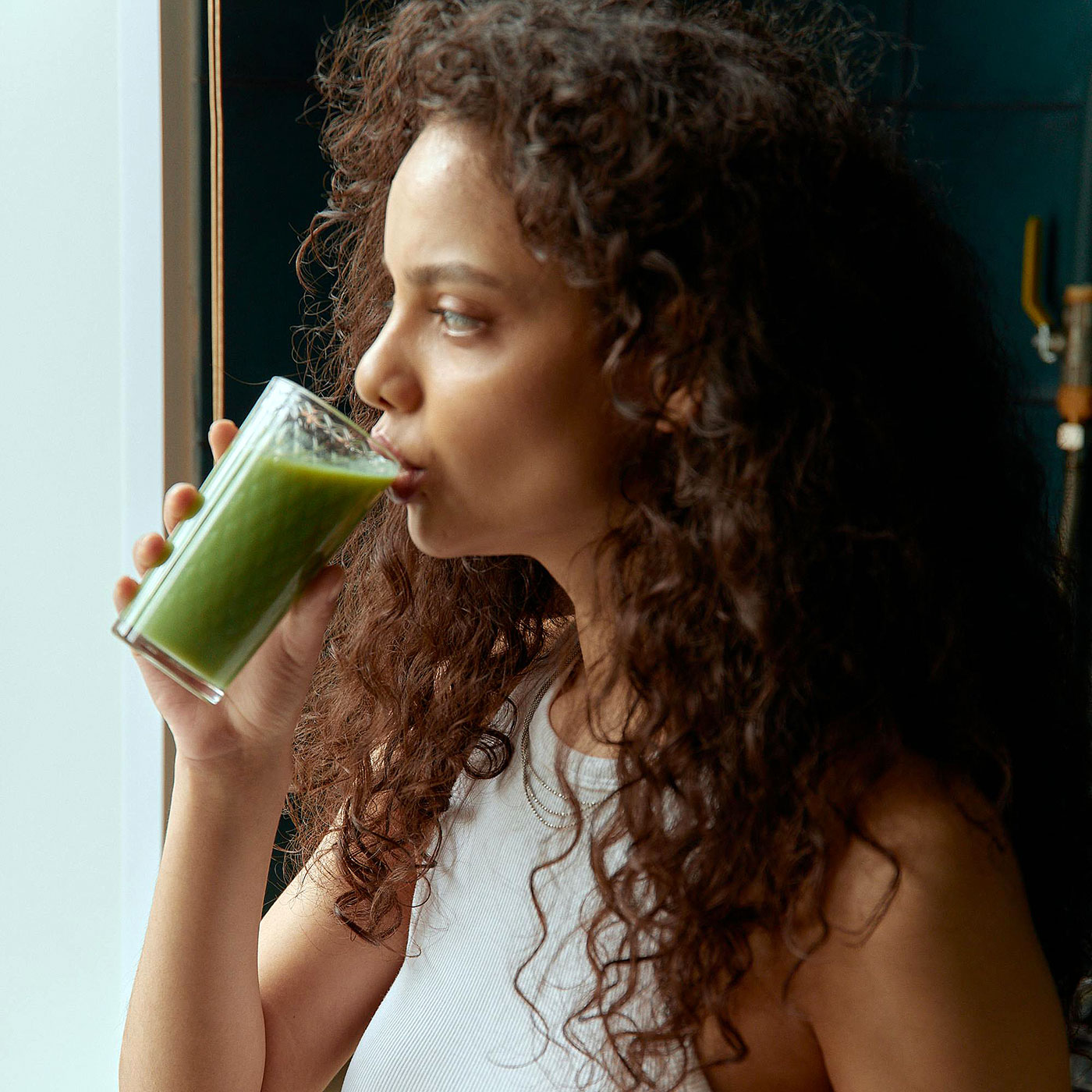 млада жена консумира чаша с разтворен зелен протеин в зеленчуков шейк