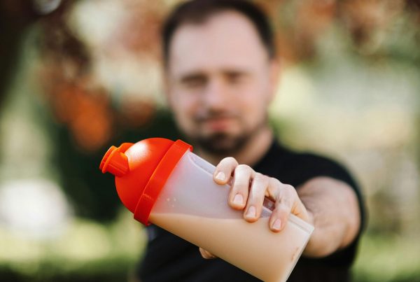 мъж държи шише с протеин на преден план