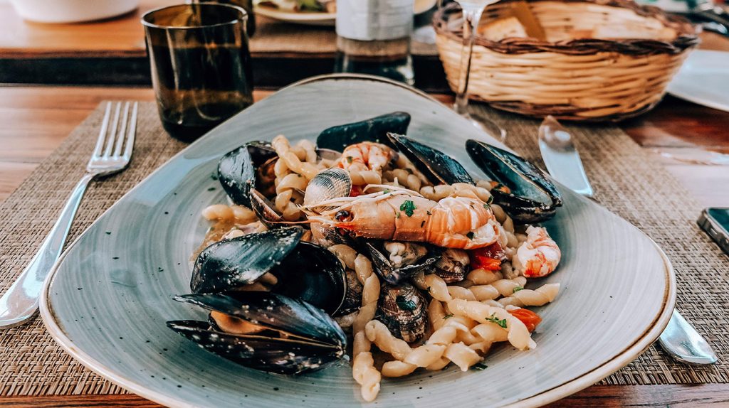 чиния със средиземноморска храна и скарида на преден план