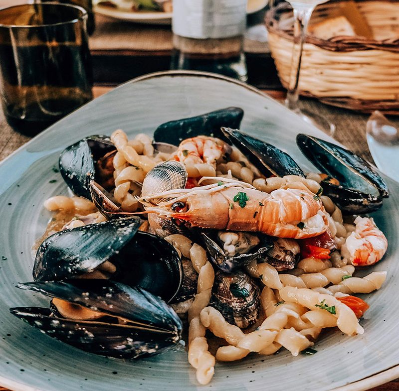 чиния със средиземноморска храна и скарида на преден план