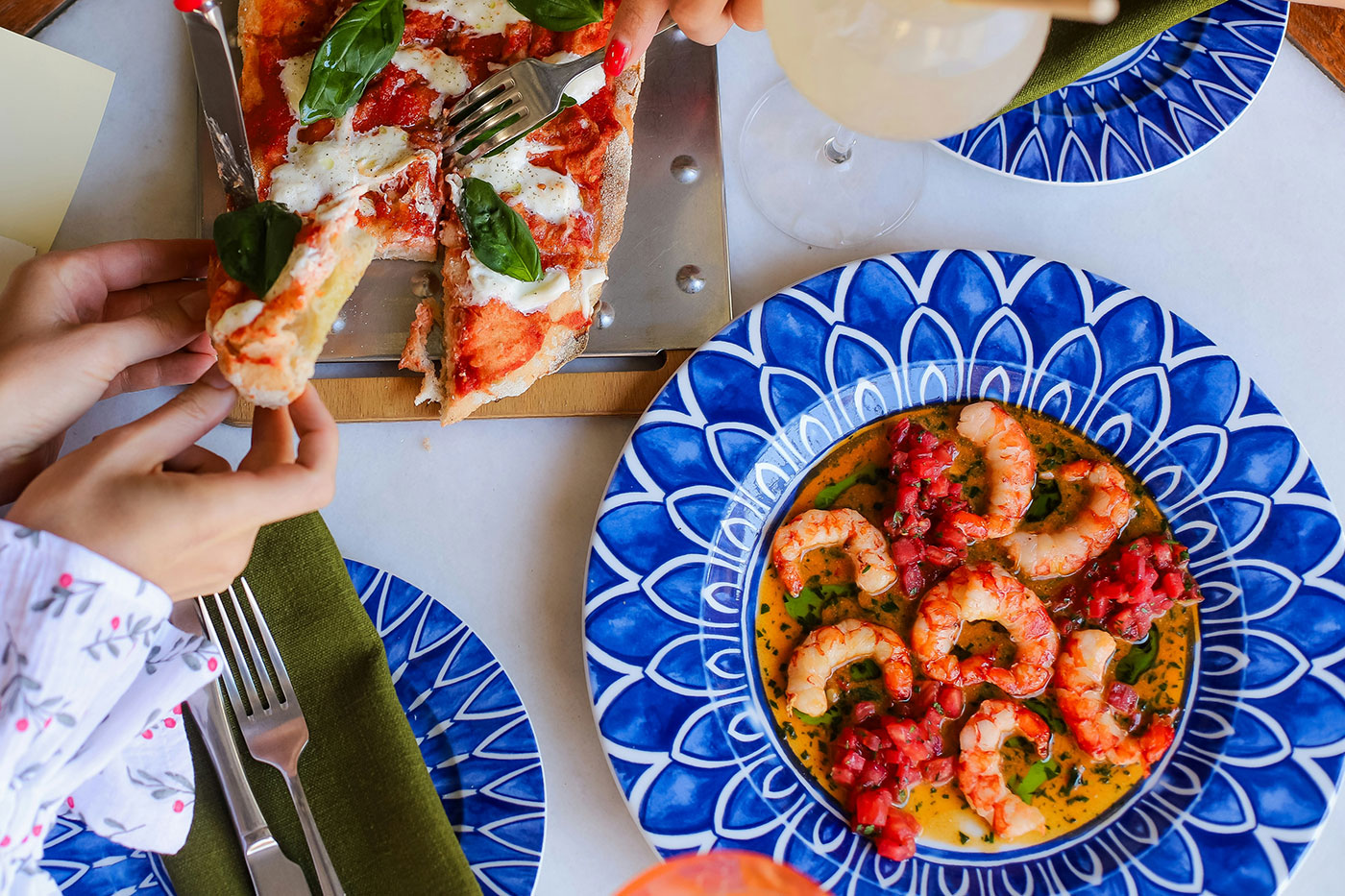 чиния със скариди по средиземноморска рецепта и дамски ръце ядат пица